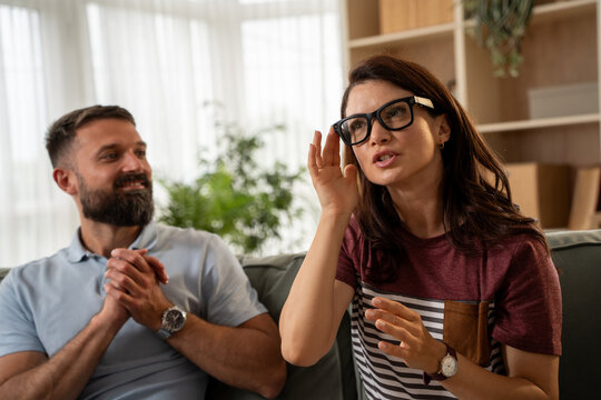 Woman using ar glasses in living room husband watching