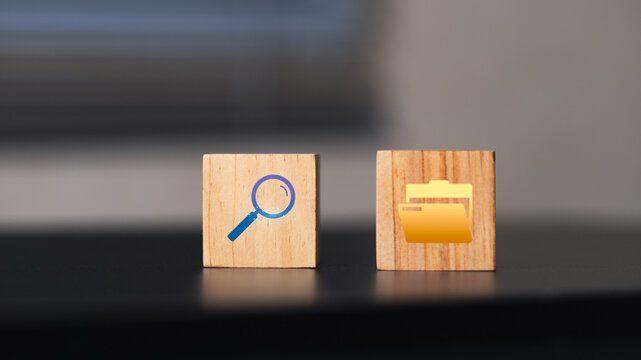 Two wooden blocks with icon symbols, one featuring a magnifying glass for search and the other a file folder for organization, on a dark surface.
