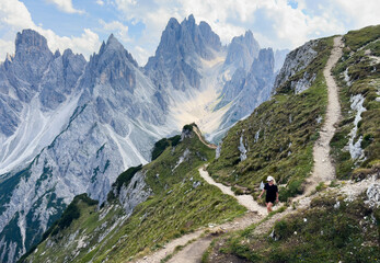 Fototapeta premium Young woman exploring hiking trail in Dolomites near Tre Cime Dolomites Italy