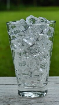 Pouring soda into an ice-filled glass in a bright garden