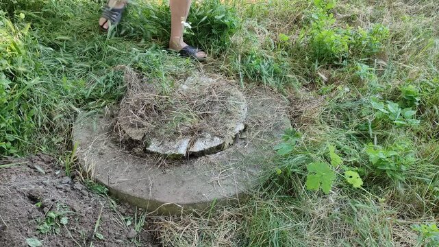 Person in gloves holding open septic tank manhole, closing it and walking away