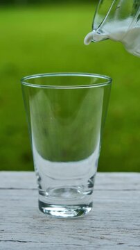 Pouring fresh milk into a glass in bright natural light