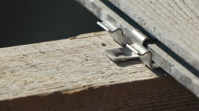 Carpenter aligning stainless steel hidden fastener onto pressure treated lumber for deck construction. Extreme macro close-up shot.