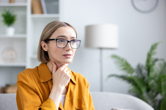 Woman touching her neck, experiencing discomfort and pain in her throat area, possibly indicating a sore throat, thyroid issue, or other health problem