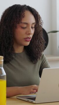 Vertical HD video of young Brazilian student closing laptop and smiling at camera. Confident female looking at the viewer after finishing an online study session at home. Online education concept