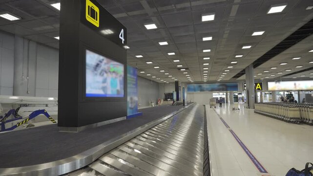 continuous flow Baggage claim conveyor belt in an airport terminal with metallic surface reflecting belt plate without luggage bag at arrival hall area in airport with sign board of flight number