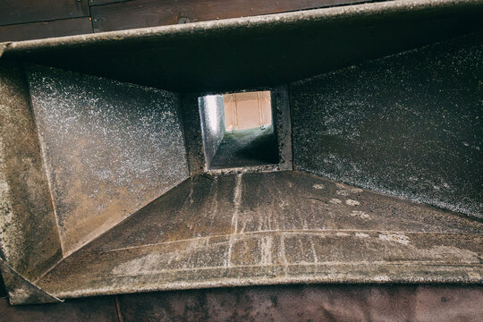 Interior view looking down a heavily dust-coated metal HVAC air duct requiring urgent professional cleaning and maintenance.