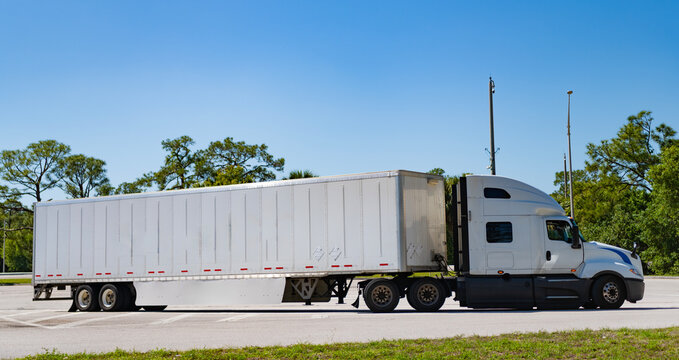 Trucking with semitruck vehicle. Semi truck in America. Freightliner trailer transportation. Rig truck semi trailer hauling. Parked truck. American style truck. Transport concept. Road freight cars