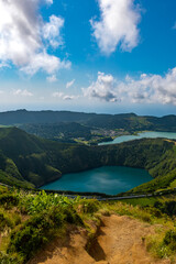 Grota do Inferno viewpoint offers a stunning view of the vibrant blue and green Sete Cidades and Santiago crater lakes surrounded by lush green slopes and distant Atlantic Ocean in São Miguel, Azores © Marta Nogueira