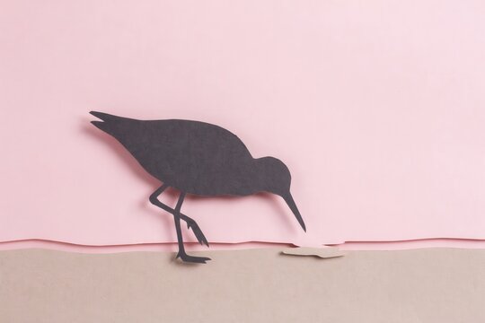Minimalist paper craft silhouette of a bird foraging on a pink and beige background landscape