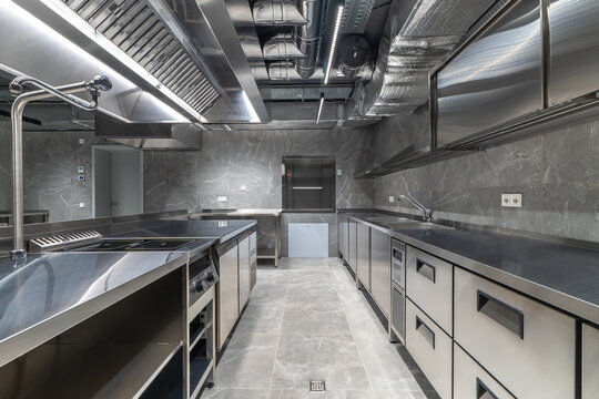 A large kitchen equipped with stainless steel appliances and marble countertops is ready for cooking. It has ample space and modern fixtures for food preparation