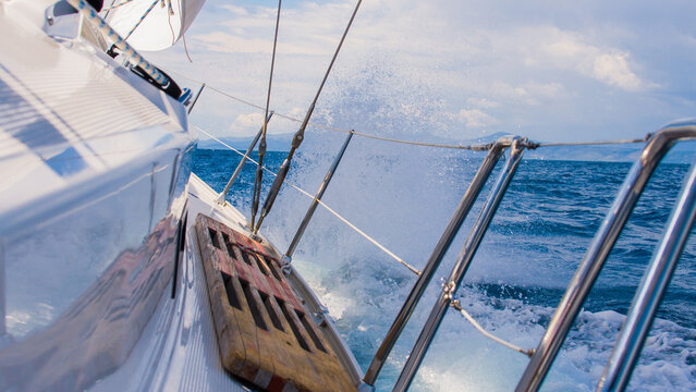 Racing yacht bow cutting through ocean waves, sailing adventure at sea