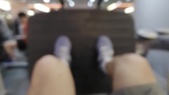 Blurred point of view shot of a person using a leg press machine at the gym. Out of focus legs and feet pushing against the equipment platform. Abstract fitness and workout background concept.