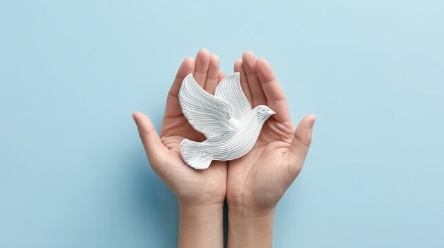 Cupped hands holding white dove ornament against pastel blue background