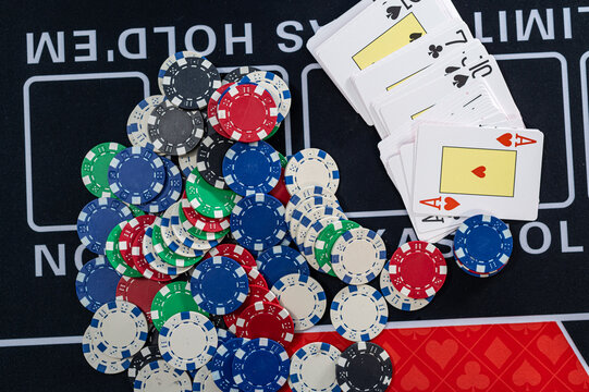 Scatter of Colorful Casino Chips and Deck of Cards on Texas Holdem Gaming Table Surface