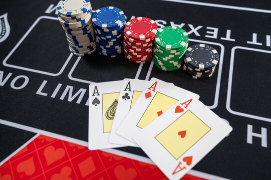 Four Aces Playing Cards Combination with Stacks of Casino Chips on Black Felt Table Surface