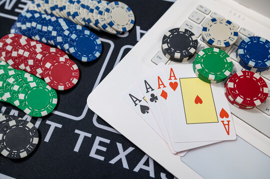 Online Casino Poker Concept with Laptop White Keypad Four Aces Cards and Stacked Gaming Chips