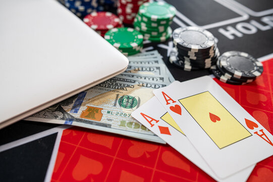 Top View of Laptop Keyboard near Hundred Dollar Bills Pocket Aces Cards and Multi Color Tokens