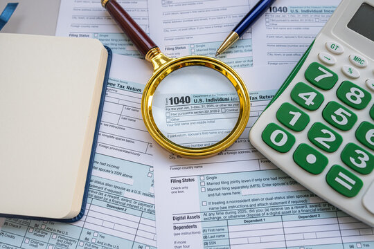 Tax Preparation Workspace with Form 1040 Magnifying Glass Calculators and Pen on Office Desk