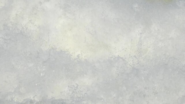 Close up slow motion video of violent whitewater churning rapidly, creating thick foam textures and dynamic spray movement across the entire frame.
