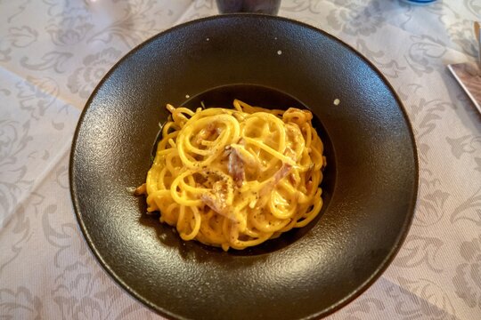 Spaghetti carbonara on a black plate for lunch