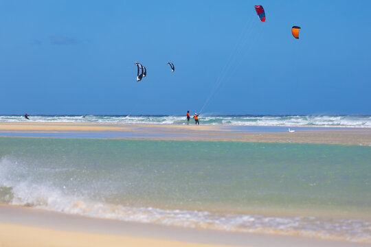 Kitesurfers on a picturesque, windy, sandy Sotavento, Costa Calma, beach with crashing waves, Canary Islands, Fuerteventura, background or wallpaper for your project	