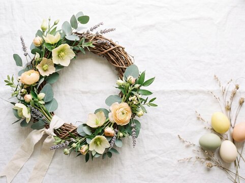 Easter wreath with flowers and pastel eggs on a white background  