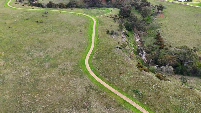 An aerial top-down view of a winding gravel walking trail following the green valley of Toolern Creek in Strathtulloh, Melbourne Australia. Shared&nbsp;path infrastructure,recreation trails, green space.