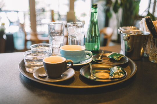 Serving tray with prepared coffee drinks and glasses of water ready for customers in a cafe