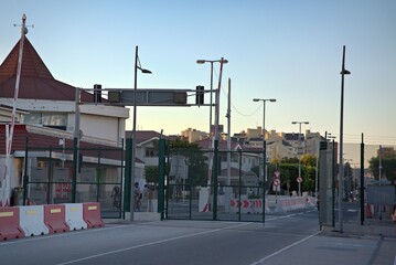 Controlled security gate entrance featuring a metal boom barrier and chain link fence on a suburban street at dusk © danr13