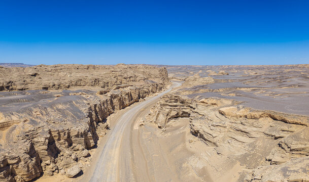 Winding dirt road through a deep canyon in the desolate yardang desert of Dahaidao, Xinjiang, China