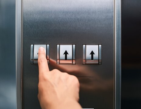 finger pressing up arrow button on elevator panel