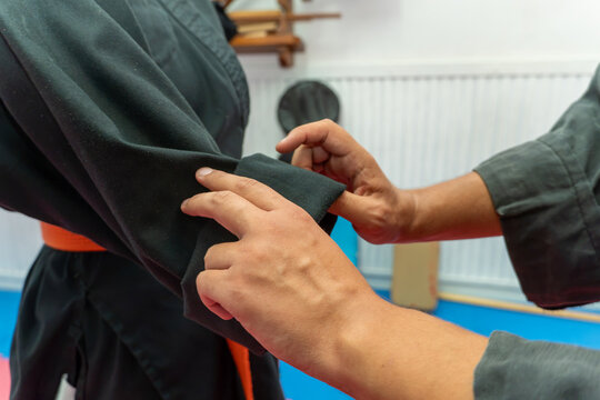 Two hands demonstrating a hapkido martial arts technique, grabbing the sleeve of a black uniform during a training session