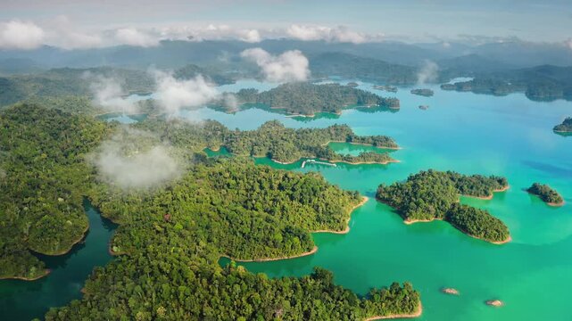 Amazing KHAO SOK National Park showing emerald green waters of Cheow Lan Lake with numerous limestone karsts. Lush green rainforest islands under a morning clouds. Aerial view drone flight panorama