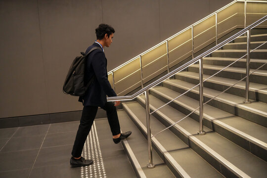 A confident male professional in a suit walking up steps on the morning commute on the stairs of a metro station, an honest snapshot of the journey to and from work