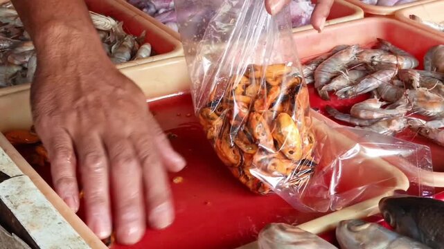 Fresh shellfish and clams being handled and packaged at a local seafood market, showing traditional food preparation and seafood trade.