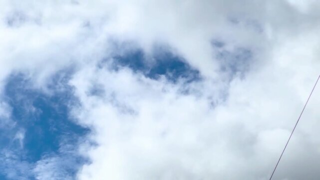 Clouds in the sky. Large white fluffy cumulus cloudscape against a deep blue sky during day-time in horizontal landscape view.