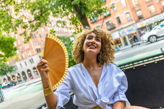 Woman cooling down with a fan on a hot new york city day