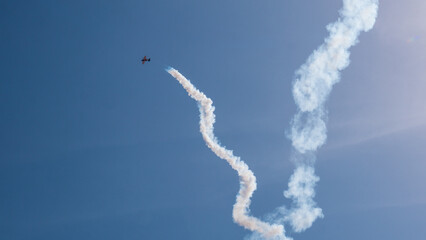 Aerobatic Biplane Trailing a White Smoke Spiral Against a Clear Blue Sky at an Air Show — Precision Flying, Freedom and Adventure Concept © Svetlana