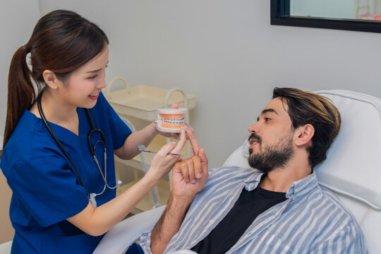 Woman dentist in dental office talking with male patient and preparing for treatment. A dentist talking to man in dentist surgery, a dental check-up.