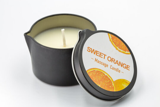 Sweet orange massage candle product closeup on white.