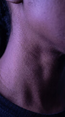 Fototapeta premium Moody dramatic closeup of male neck and throat anatomy highlighted in purple neon lighting