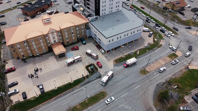 Aerial view captures the tension as firefighters respond to an emergency at a hotel in Halifax, Nova Scotia. Evacuated guests stand anxiously on the street, waiting for news