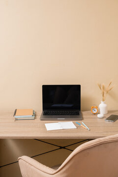 Workspace with laptop and stationery on wooden desk in a simple room