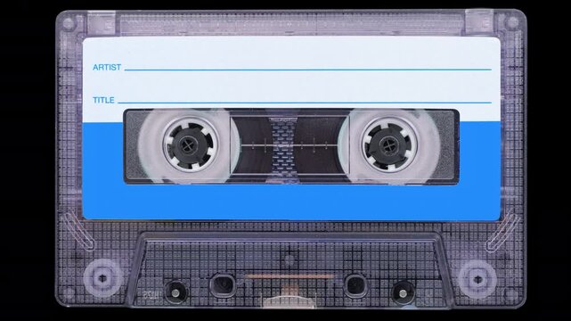 Vintage Audio Cassette Reels Spinning. Front view of a  cassette with reels rotating steadily on a black background.