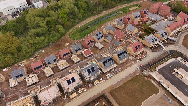 Aerial view of a new residential housing development under construction with multiple houses in various stages of completion and solar panels in Hoddesdon, England, United Kingdom.