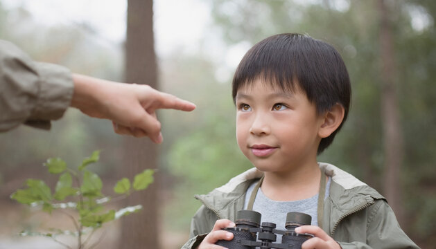 Child Holding Binoculars with Adult Gesturing in Nature