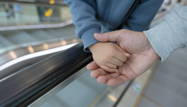 Parent and Child Holding Hands on Escalator