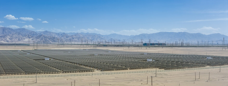 Solar Photovoltaic Power Station with Transmission Towers and Substation beneath Kunlun Mountains in Gobi Desert