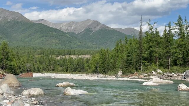 Video of summer landscape of Irkut River and Eastern Sayan Mountain range in distance on sunny August day. Natural background. Summer travels. Siberia, Buryatia, Tunka Valley, Nature foothill park